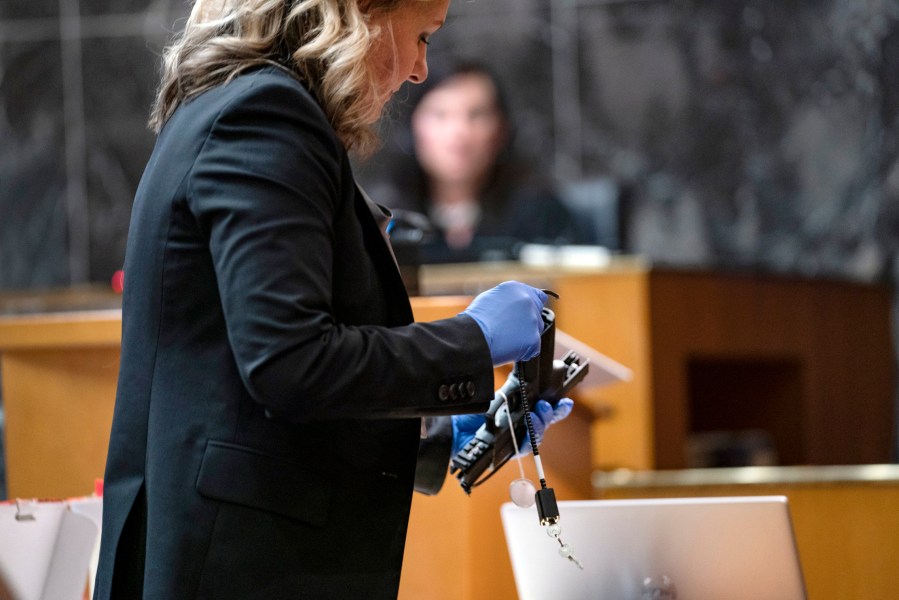 Oakland County Prosecutor Karen McDonald demonstrates how swiftly she was able to insert a gun lock during closing statements in the trial of James Crumbley, Wednesday, March, 13, 2024 in Pontiac, Mich. Crumbley is charged with involuntary manslaughter, accused of failing to secure a gun at home and ignoring his son's mental health. Ethan Crumbley killed four students at Oxford High School in 2021. (Mandi Wright/Detroit Free Press via AP, Pool)