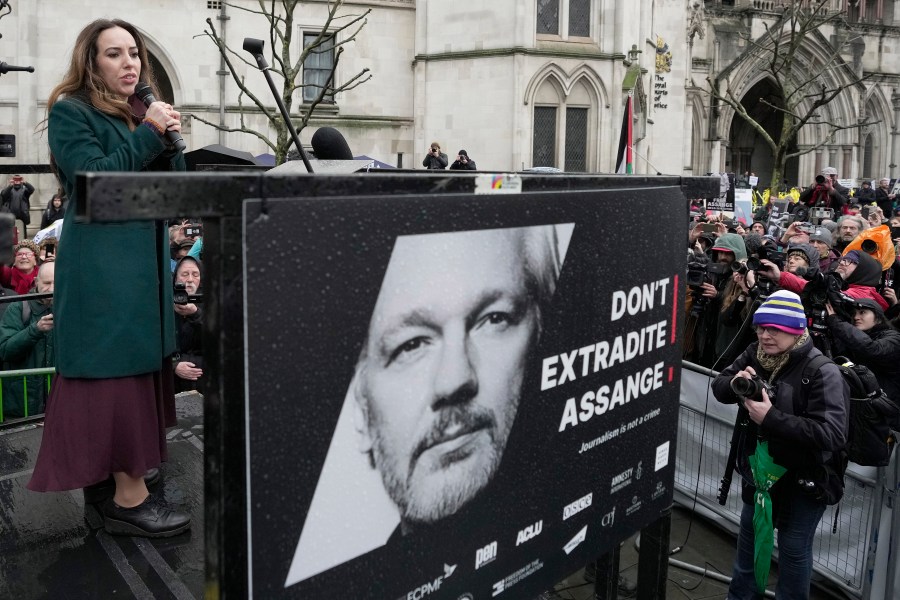 FILE - Stella Assange, wife of Julian Assange, speaks besides a poster of Julian Assange at the Royal Courts of Justice in London, Wednesday, Feb. 21, 2024. A London court is due to rule whether WikiLeaks founder Julian Assange can challenge extradition to the United States on espionage charges. Two judges will issue a ruling Tuesday morning in the High Court on whether Assange can make one final appeal in England. (AP Photo/Kin Cheung, File)