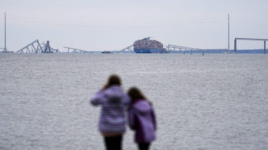 People look at the collapsed Francis Scott Key Bridge from a distance.