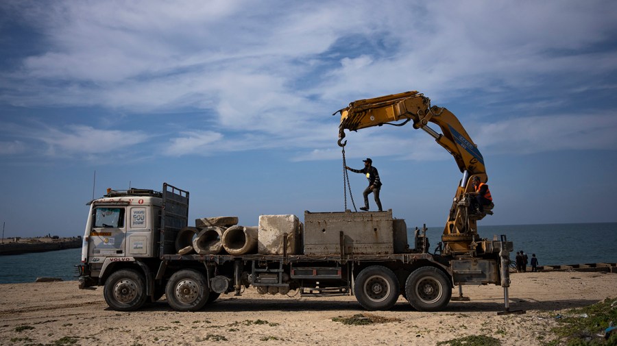 A worker helps move cement blocks on a truck.