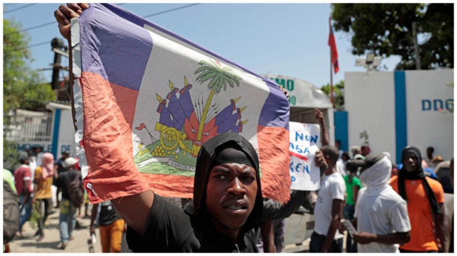 A demonstrator holds up a Haitian flag during a protest against insecurity in Port-au-Prince, Haiti, Monday, Aug. 7, 2023. (AP Photo/Odelyn Joseph)