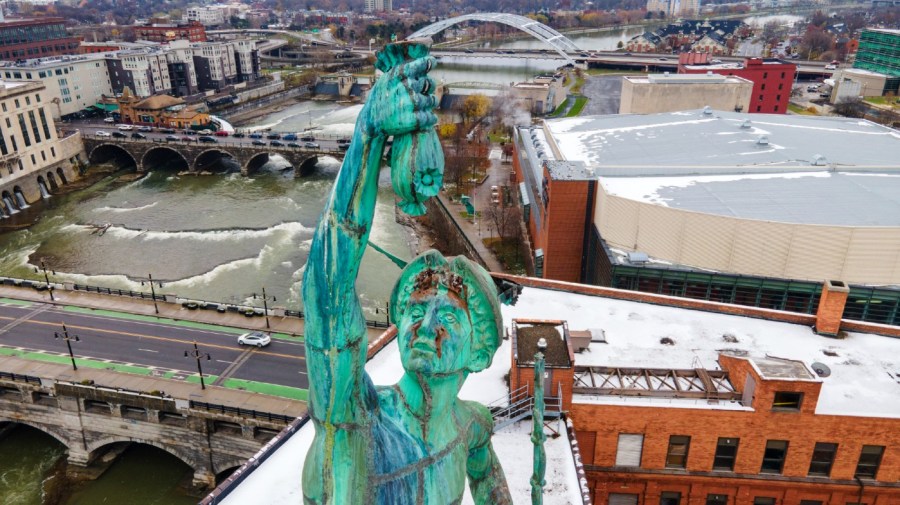 A statue of Mercury, the Roman god of commerce, holds a bag of money in his right hand atop the Aqueduct Building in Rochester, New York, on Sunday, November 28, 2021.