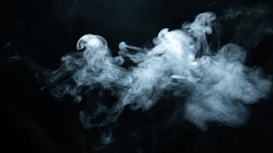 White smoke wafts across a dark background.