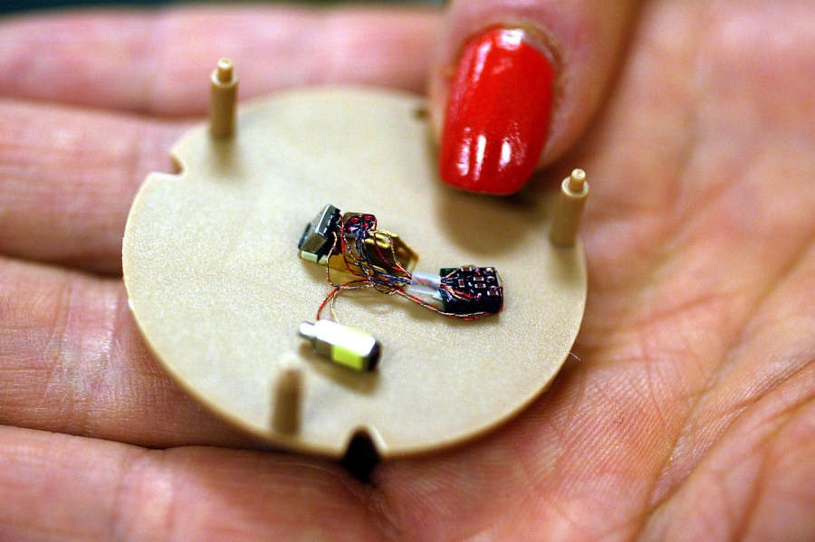 In this July 12, 2004, file photo, a woman holds a hearing aid that uses artificial intelligence in Somerset, N.J.