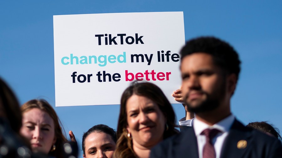 A Tik Tok creator holds a sign