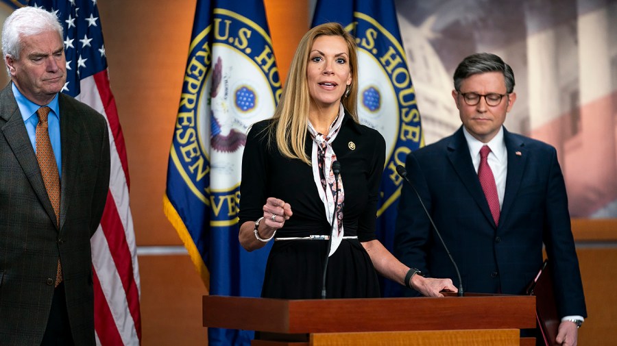 Representative Beth Van Duyne speaks at a podium as House Speaker Mike Johnson stands to the side.