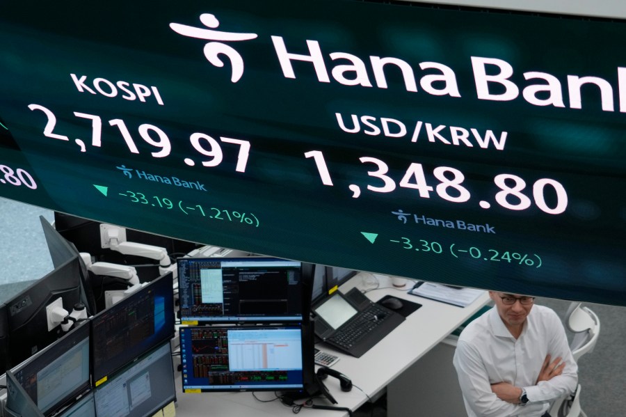 A currency trader passes by the screen showing the Korea Composite Stock Price Index (KOSPI), left, and the foreign exchange rate between U.S. dollar and South Korean won at the foreign exchange dealing room of the KEB Hana Bank headquarters in Seoul, South Korea, Wednesday, April 3, 2024. Asian shares mostly declined Wednesday after Wall Street sank, hitting the brakes on what’s been a nearly unstoppable romp. (AP Photo/Ahn Young-joon)