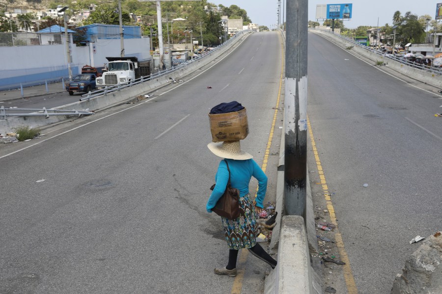 A street vendor crosses a street that is empty due to residents staying home amid gang violence in Port-au-Prince, Haiti, Monday, April 8, 2024. (AP Photo/Odelyn Joseph)