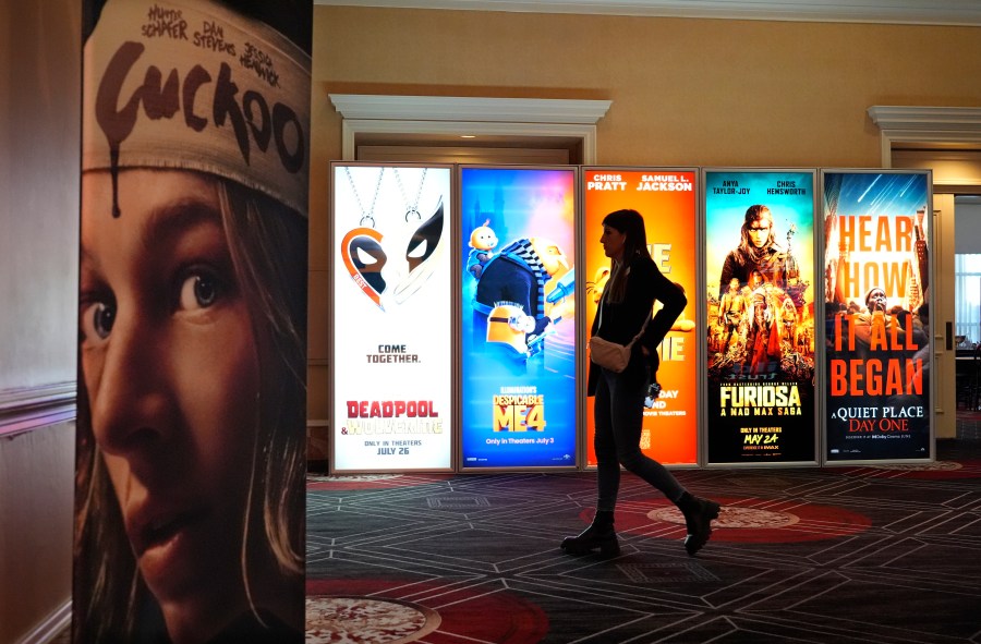 A visitor walks past advertisements for upcoming movies on the opening day of CinemaCon 2024 at Caesars Palace, Monday, April 8, 2024, in Las Vegas. The four-day convention of the National Association of Theatre Owners (NATO) runs through Thursday. (AP Photo/Chris Pizzello)