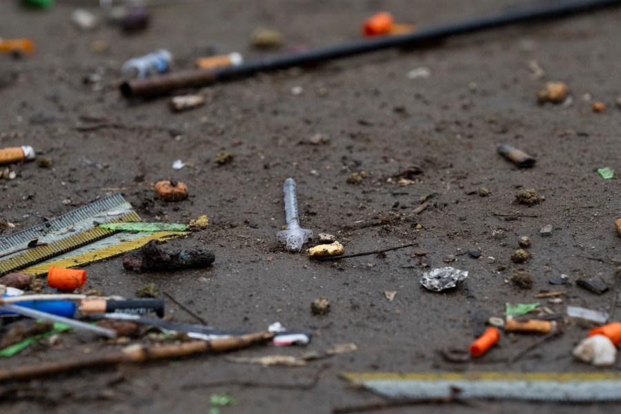 A used needle is seen next to orange syringe caps on the ground on Friday, March 22, 2024, in Baker Park in Grants Pass, Ore. (AP Photo/Jenny Kane)