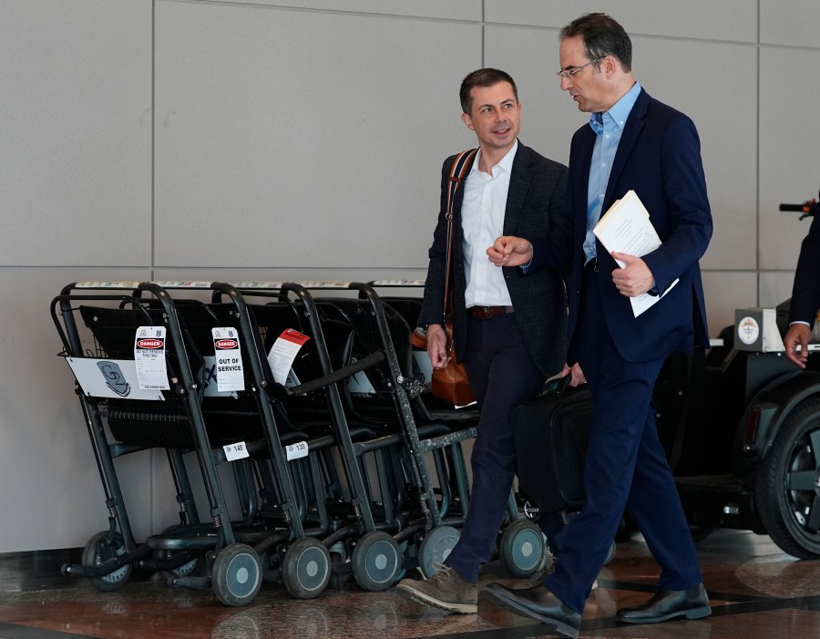 U.S. Transportation Secretary Pete Buttigieg, left, confers with Colorado Attorney General Phil Weiser as they head to a news conference to announce a new partnership that will streamline how consumer complaints against airlines are resolved in the terminal at Denver International Airport Tuesday, April 16, 2024, in Denver. (AP Photo/David Zalubowski)