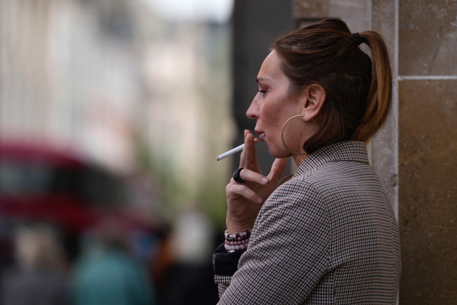 A woman smokes on a street, in London, Tuesday, April 16, 2024. A bold plan to ban anyone born after 2008 from ever legally buying cigarettes in Britain faces its first test in Parliament. The bold plan has divided the governing Conservatives, with some hailing its public health benefits and others condemning it as state overreach. (AP Photo/Kin Cheung)