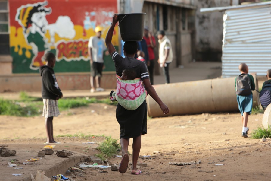 FILE - A woman carries a her baby and a bucket of water in Harare on April 6, 2020. A new study says an African woman is roughly 130 times more likely to die from pregnancy and childbirth complications than a woman in Europe or North America, the U.N. population fund reported Wednesday, April 17, 2024, as it decried widening inequality in sexual and reproductive health and rights worldwide. (AP Photo/Tsvangirayi Mukwazhi, File)