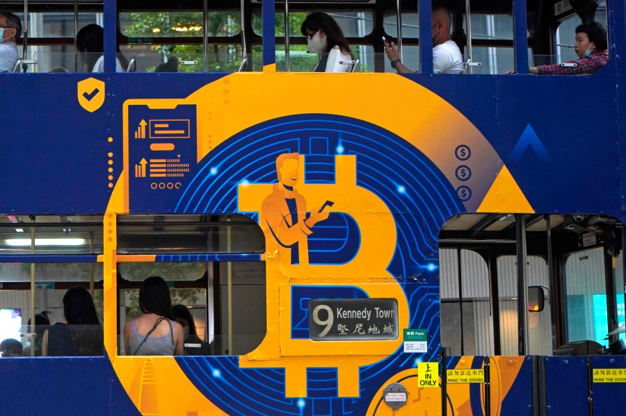 FILE - An advertisement for the cryptocurrency Bitcoin displayed on a tram, May 12, 2021, in Hong Kong. Sometime in the next few days or even hours, the “miners” who chisel bitcoins out of complex mathematics are going to take a 50% pay cut — effectively slicing new emissions of the world’s largest cryptocurrency in an event called bitcoin halving. (AP Photo/Kin Cheung, File)