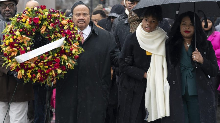 Martin Luther King III hold a wreath in honor of his father as he walks with his daughter and wife.