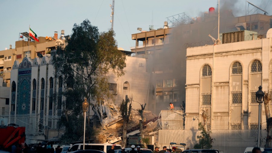 Emergency services work at a destroyed building hit by an air strike.