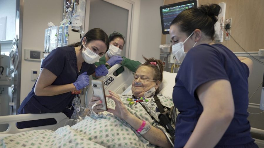 Lisa Pisano and medical personnel look at her phone in a hospital room.