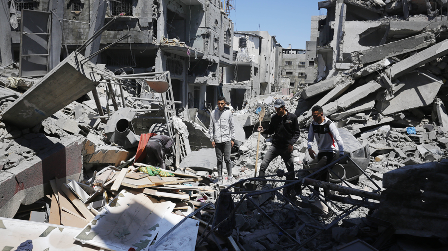 Palestinians collect the usable items among the rubble of the destroyed buildings.