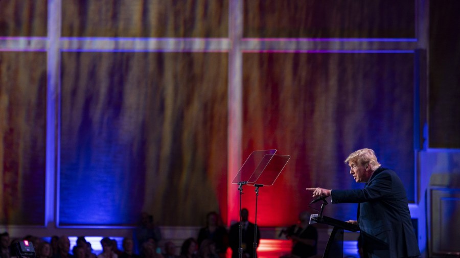 Donald Trump gestures to the crowd on stage.