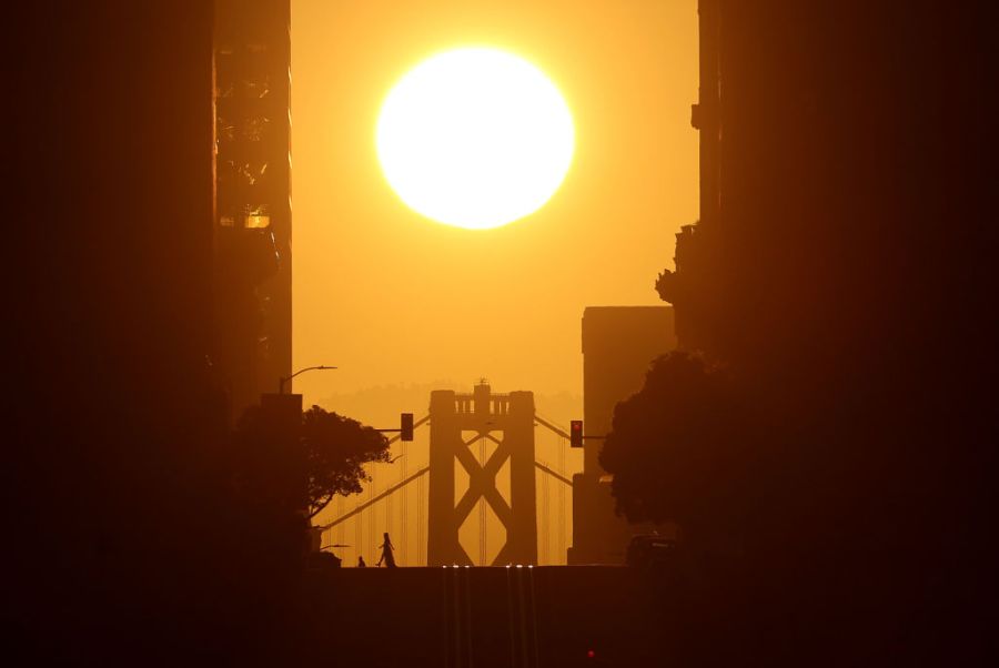 The sun rises behind the San Francisco-Oakland Bay Bridge.