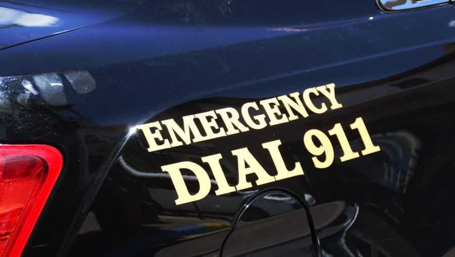 A close-up of a police car shows a decal that reads "Emergency Dial 911."