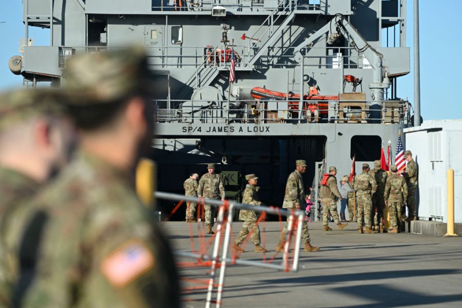 Military personnel work near a vessel preparing to leave for the Middle East.