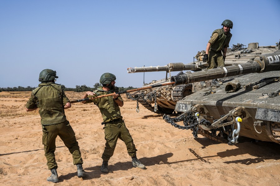 Israeli soldiers work on a tank at a staging ground near the border with the Gaza Strip, in southern Israel, Sunday, May 5, 2024. (AP Photo/Tsafrir Abayov)