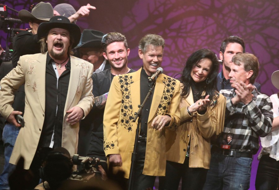 FILE - Travis Tritt, left, Randy Travis, center left, Mary Travis, center right, and Ricky Traywick, right, appear on stage at the "1 Night. 1 Place. 1 Time.: A Heroes and Friends Tribute to Randy Travis" on Feb. 8, 2017 in Nashville, Tenn. (Photo by Laura Roberts/Invision/AP, File)