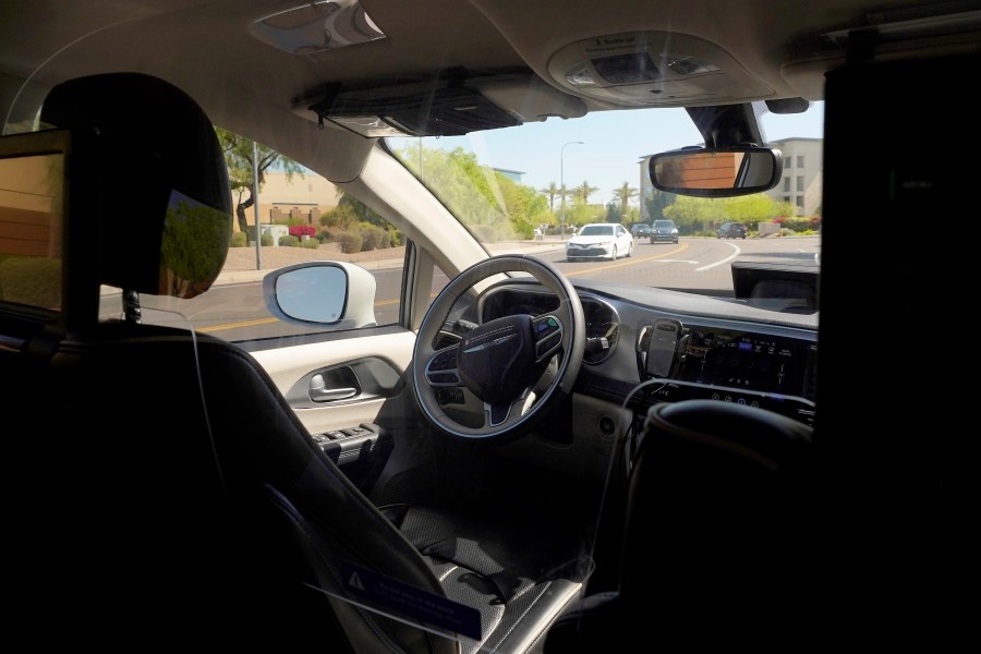 FILE - A Waymo minivan moves along a city street as an empty driver's seat and a moving steering wheel drive passengers during an autonomous vehicle ride, on April 7, 2021, in Chandler, Ariz. The U.S. government's highway safety agency has opened another investigation of automated driving systems, this time into crashes involving Waymo's self-driving vehicles. The National Highway Traffic Safety Administration posted documents detailing the probe on its website early Tuesday after getting 22 reports of Waymo vehicles either crashing or doing something that may have violated traffic laws. (AP Photo/Ross D. Franklin, File)