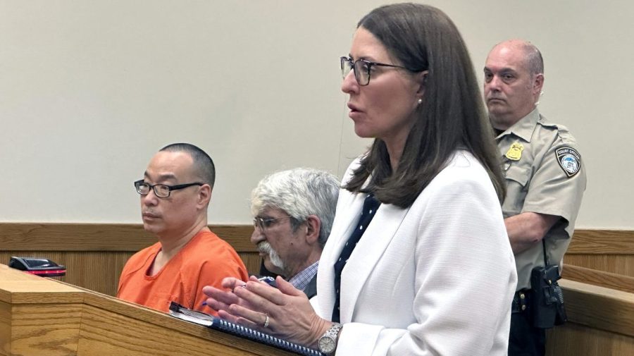 Michigan Assistant Attorney General Shawn Ryan speaks in court in Howell, Mich., on Friday, May 17, 2024. A judge set a trial date for Glenn Chin, seated in orange. He's a pharmacist blamed for 11 deaths linked to contaminated steroids made in 2012 at a Massachusetts specialty lab. (AP Photo/Ed White)