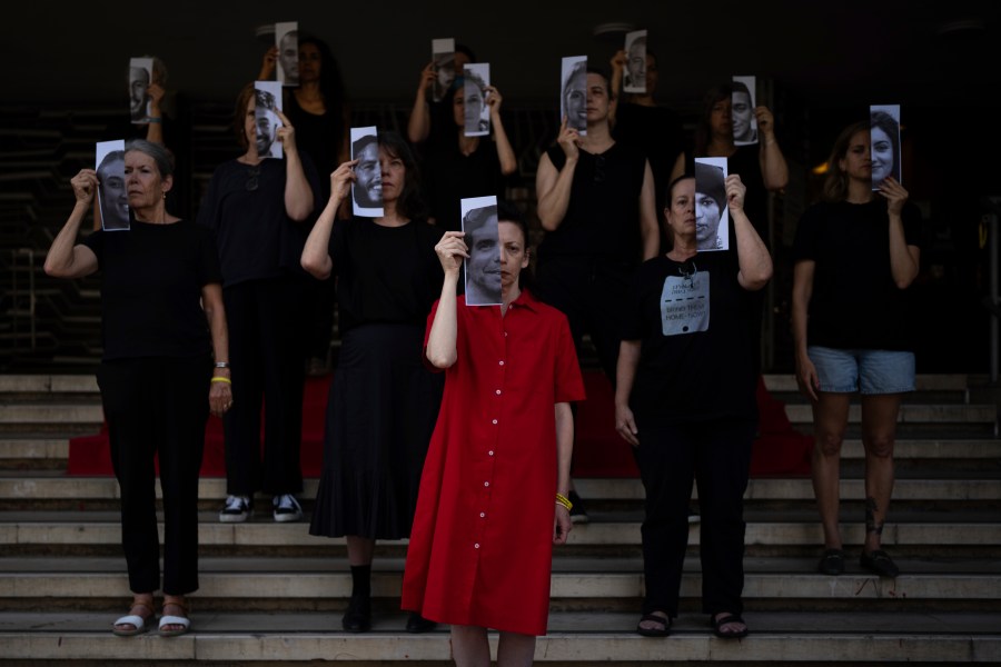 Relatives and supporters of Israeli hostages held by Hamas in Gaza hold photos of their loved ones during a performance calling for their return in Tel Aviv, Israel, Thursday, May 23, 2024. (AP Photo/Oded Balilty)