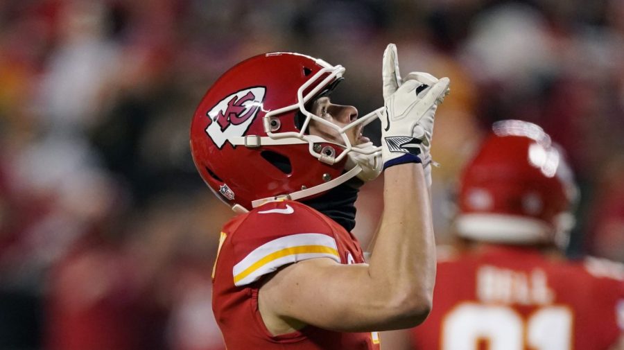 Kansas City Chiefs kicker Harrison Butker raises his hands in celebration on the field.