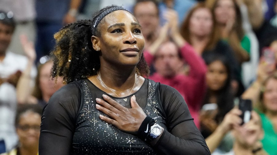 Serena Williams places her hand on her chest while looking out to the crowd during a tennis match.