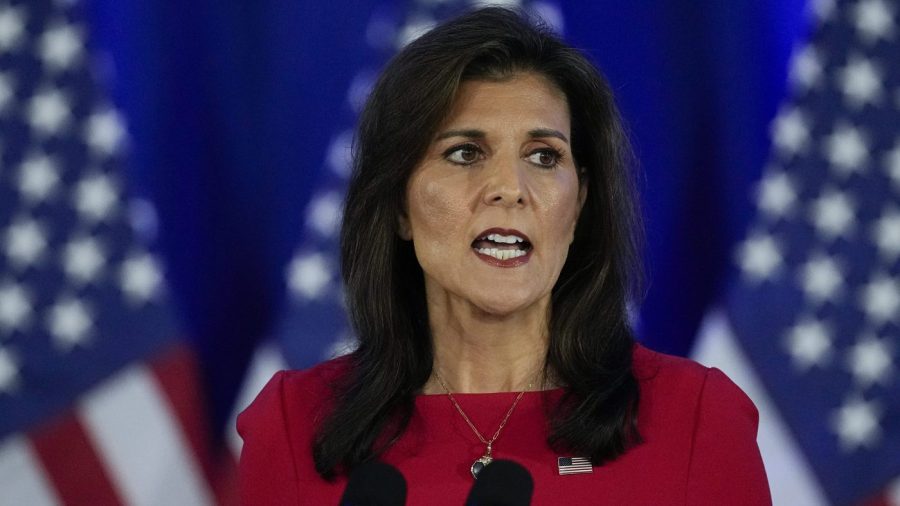 Nikki Haley speaks at an event with American flags displayed behind her.