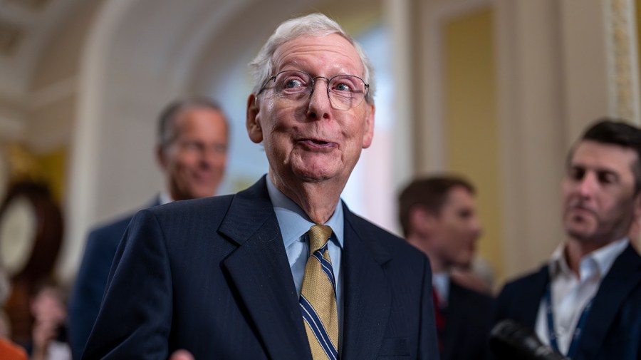 Senate Minority Leader Mitch McConnell smiles as he speaks to reporters.