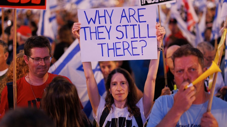 A protester holds up a sign saying "Why are they still there?" in a demonstration calling for the release of Israeli hostages held by Hamas.