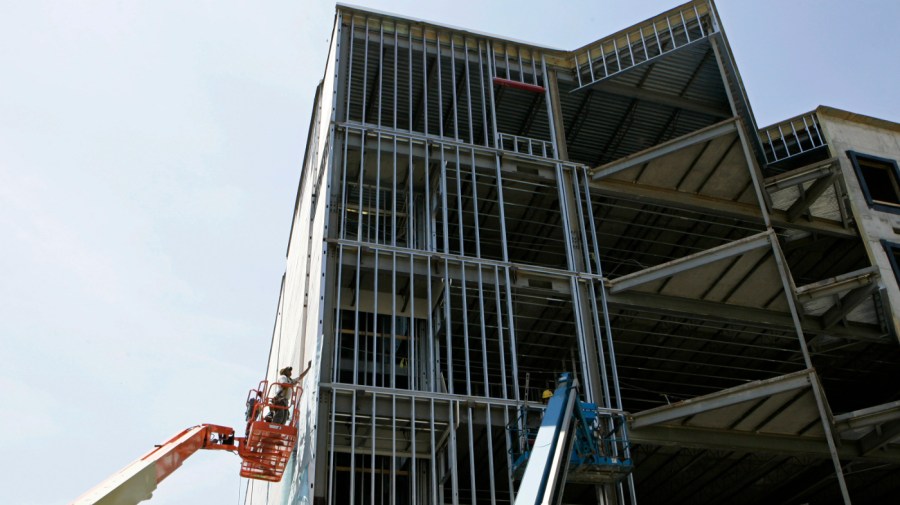 A worker afixes sheeting to the side of a new condominium building being built in Louisville, Ky., Tuesday, July 1, 2008.