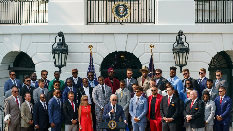 President Biden speaks during a ceremony at White House surrounded by football players.