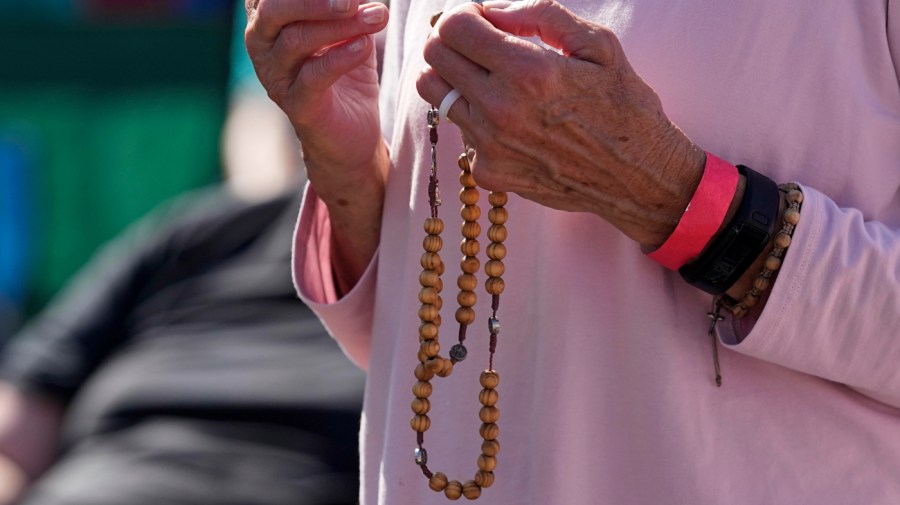 An attendee holds a rosary as she prays during a "rosary rally" on Sunday, Aug. 6, 2023, in Norwood, Ohio.