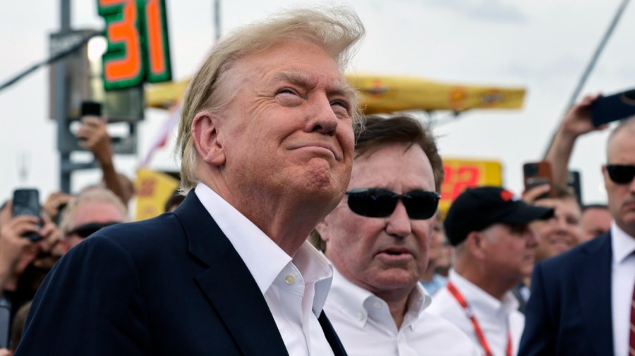 Former President Donald Trump smiles as a military jet does a flyover while he attends the NASCAR Coca-Cola 600 auto race, Sunday, May 26, 2024, in Concord, N.C. It is the first time that a president or former president has attended a race at Charlotte Motor Speedway. (AP Photo/Chris Seward)