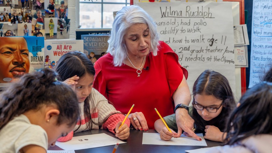 A teacher helps students with an assignment.