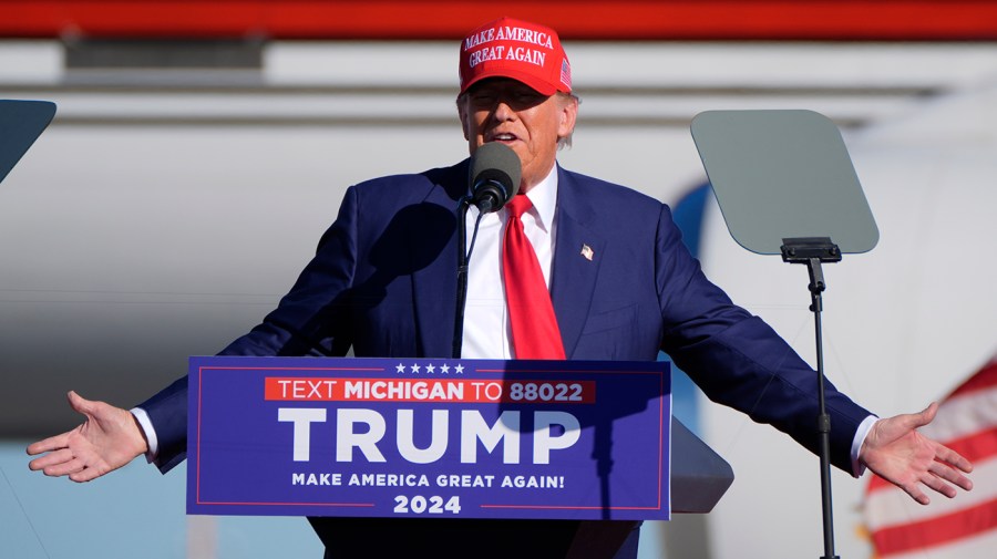 Former President Trump holds his arms wide while speaking at a campaign event.