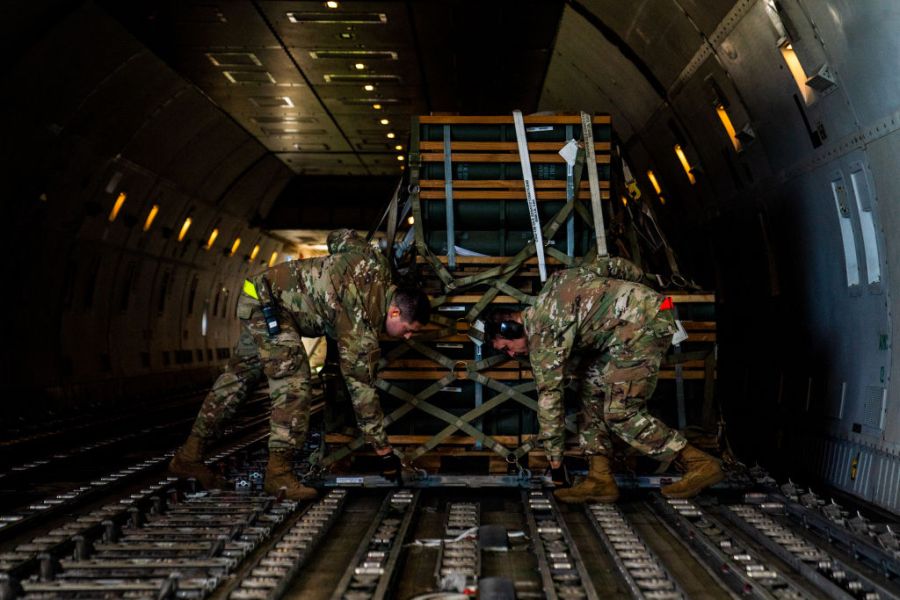 Two service members lock pallets on an airplane.