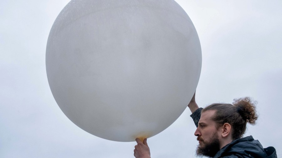 A member of a weather team prepares a weather balloon for release during a NOAA media day to learn about a field campaign to study tornadoes, in Memphis, Tennessee on February 8, 2023.