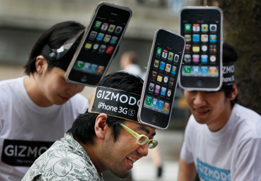 FILE - iPhone fans share a light moment while waiting for the first day sales of iPhone 3GS in Tokyo, Japan, Friday, June 26, 2009. Longtime technology news and review site Gizmodo has been sold for the third time in the past eight years. (AP Photo/Junji Kurokawa, File)