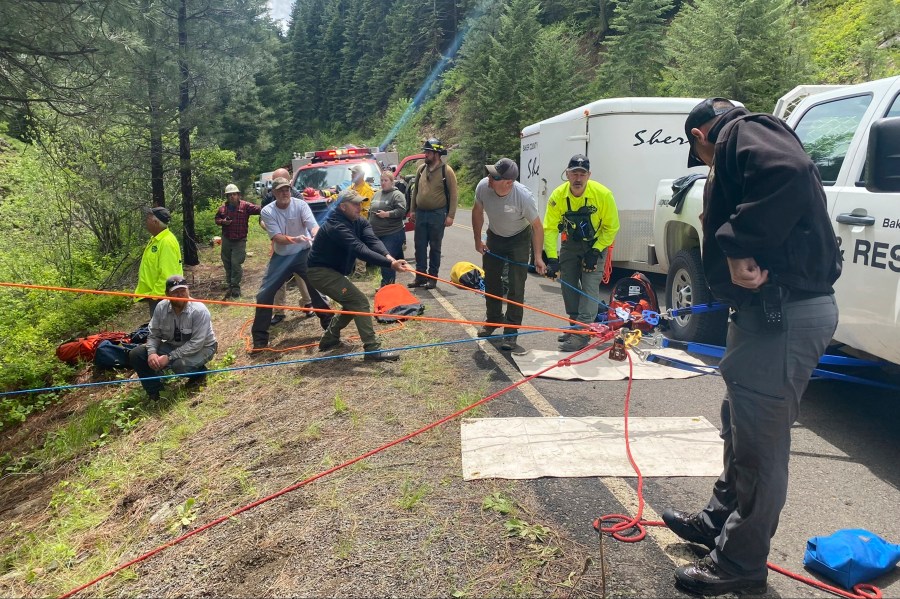 In this image provided by the Baker County Sheriff's Office, responders aid in rescue efforts after a vehicle went into an embankment on U.S. Forest Service Road 39 on June 3, 2024, in Oregon. A dog helped his owner get rescued after the crash by traveling nearly four miles to the campsite where the man was staying with family, which alerted them that something was wrong, authorities said. (Baker County Sheriff's Office via AP)