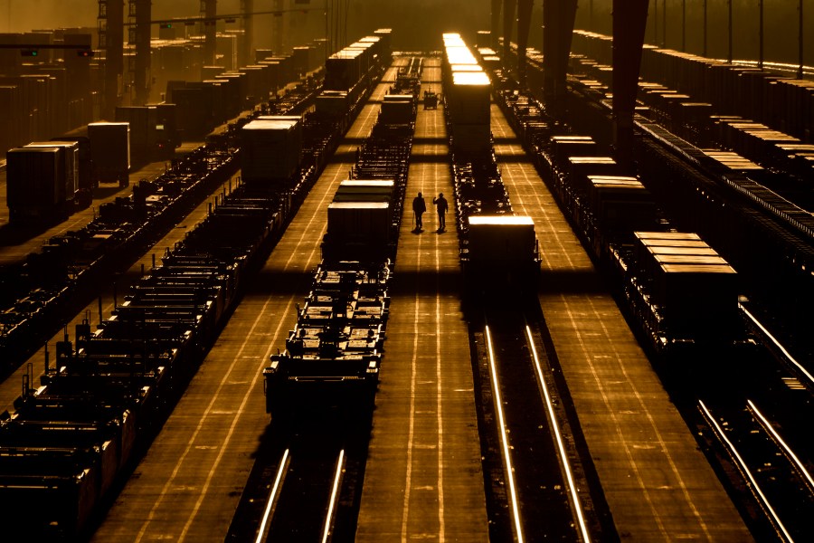 FILE - Workers walk among shipping containers in a loading area at a BNSF intermodal terminal, Jan. 3, 2024, in Edgerton, Kan. The World Bank upgraded the outlook for the global economy in 2024, citing continued resilience and strength in the United States. (AP Photo/Charlie Riedel, File)