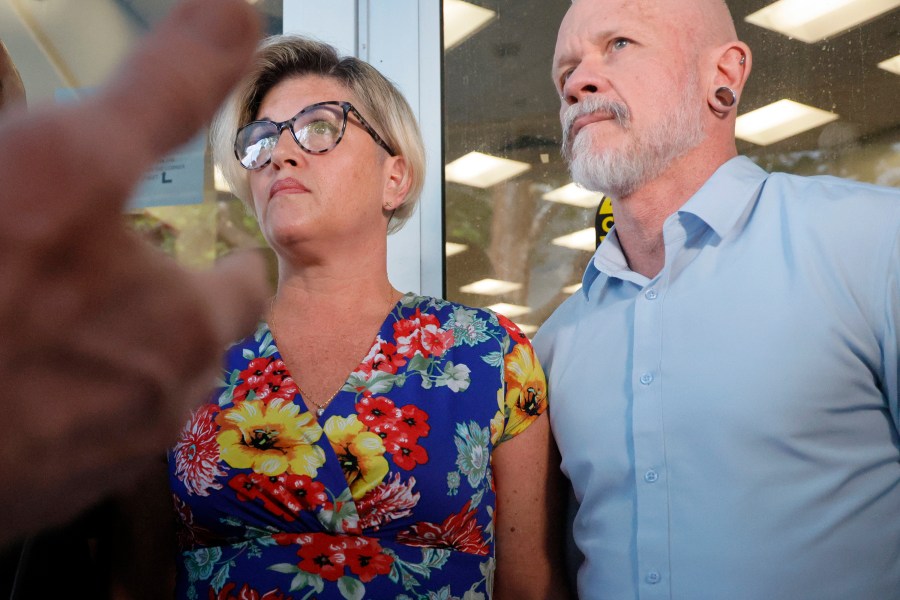 Jessica Norton, with her husband, Gary, speaks with reporters outside of a Broward County School Board meeting in Fort Lauderdale held on Tuesday, June 18, 2024. Norton, whose daughter played on the Monarch High School volleyball team, was one of five Monarch officials removed from the school Nov. 27 amid an inquiry into possible violations of the "Fairness in Women's Sports Act," a 2021 law that bans transgender girls from playing on girls' sports teams. Norton is the only one facing potential discipline. (Amy Beth Bennett/South Florida Sun-Sentinel via AP)