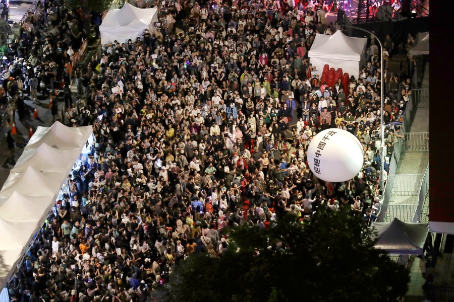 Supporters of the ruling Democratic Progressive Party (DPP) gather and push an ball reading ''Reject China's Interference In Politics'' outside of the legislative building in Taipei, Taiwan, Tuesday, May 28, 2024. (AP Photo/Chiang Ying-ying)