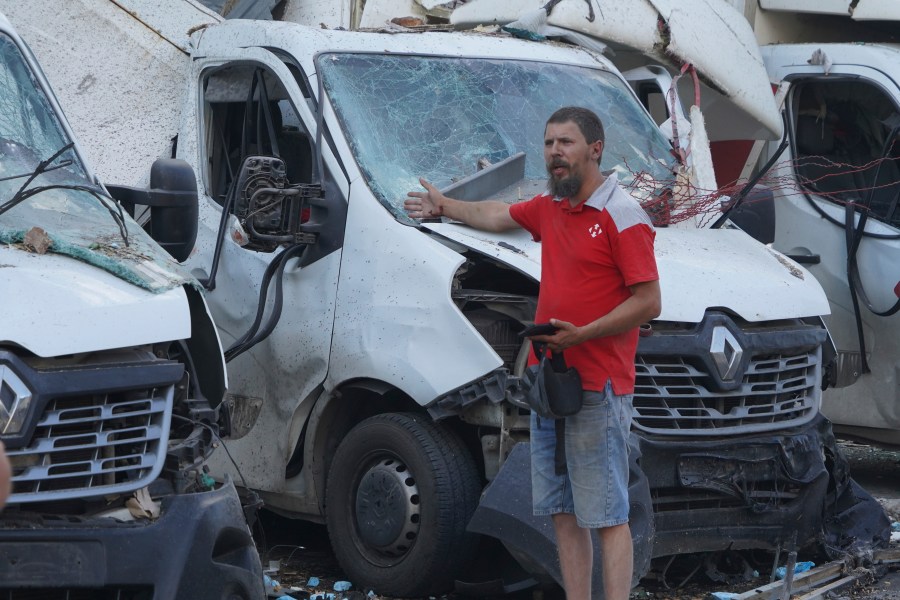 A worker of Nova Poshta delivery gestures in front of destroyed trucks after a Russian attack on his office, in Kharkiv, Ukraine, Sunday, June 30, 2024. At least one person was killed and several injured. (AP Photo/Andrii Marienko)